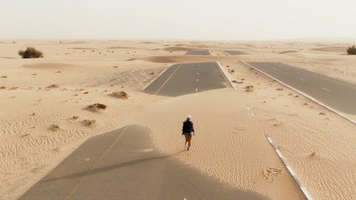 A Woman Walking on a Road in the Desert