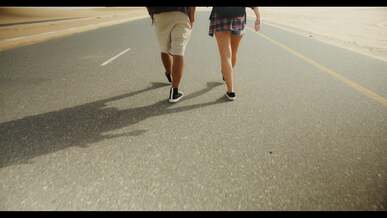 man and woman walking on a road built on a desert