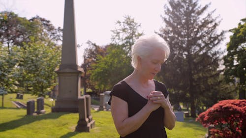 An Elderly Woman Grieving at the Cemetery