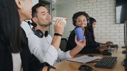 A Male Call Center Agent Holding a Coffee and a Sandwich