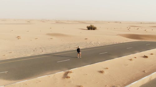 A Female Backpacker Walking on a Remote Road 
