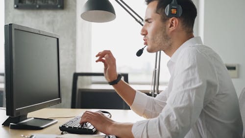 Man Wearing Headset Using a Computer