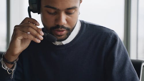 A Male Call Center Agent Talking on a Headset