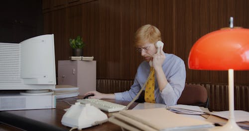 A Man Talking on the Phone while Using a Computer