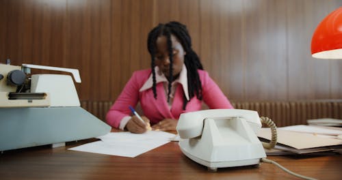 A Woman Answering a Rotary Telephone at an Office