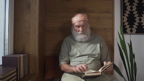 An Elderly Man Flipping Pages of a Book