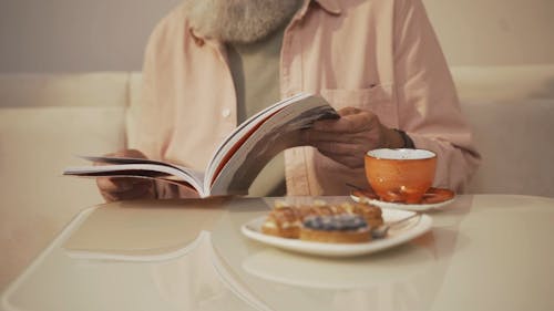 Close up of an Elderly Man Reading a Book at a Coffee Shop