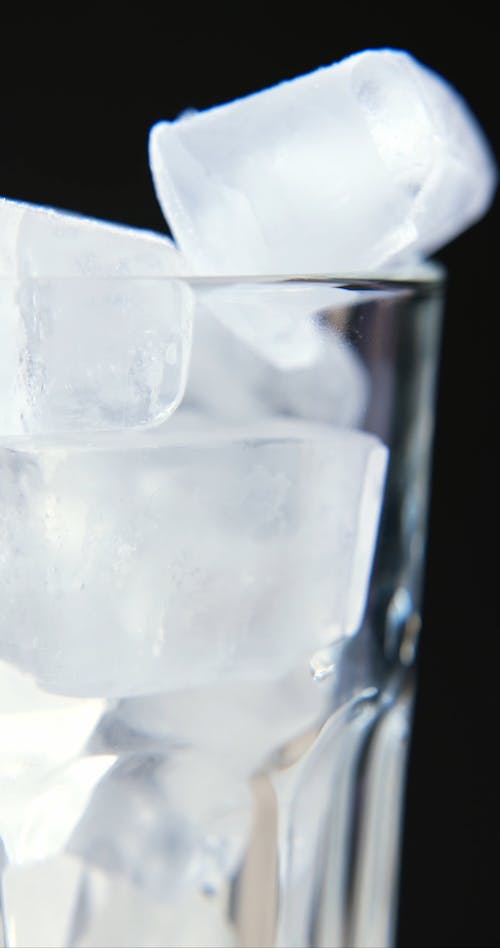 Extreme Close up of Cola being Poured into a Glass Filled with Ice