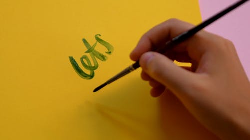Close up of a Person Writing on Paper with a Paintbrush