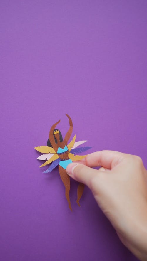 Video of Hand Placing Paper Cutouts on a Violet Background 