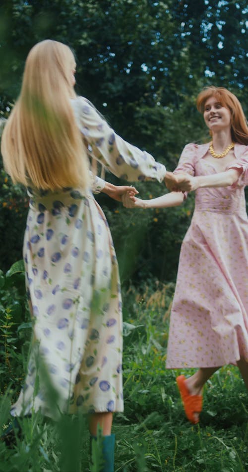Women Holding Hands and Dancing in a Lush Environment