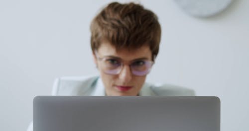 A Woman Peeking behind a Laptop