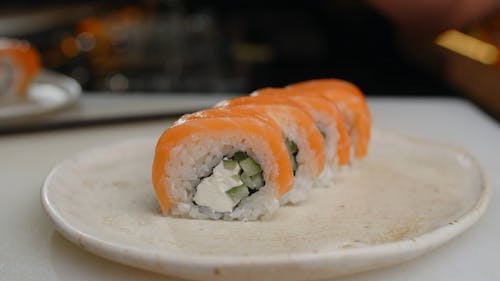 A Person Placing Mayonnaise on Sushi Rolls