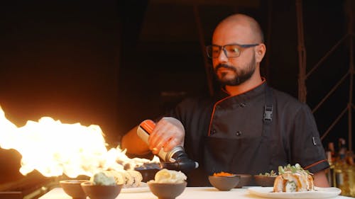 A Chef Using a Blowtorch on Sushi Rolls