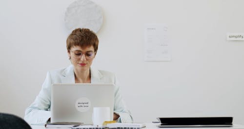 Woman Talking on the Phone While Looking at the Screen of a Laptop