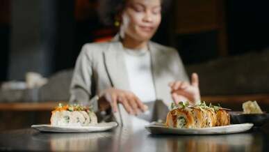 a smiling woman eating with chopsticks