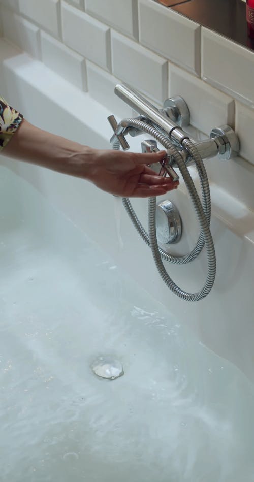 Person Turning On the Water In the Bathtub