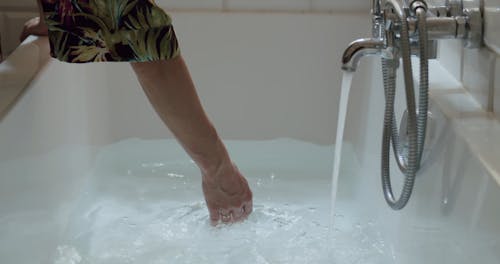 Person Touching the Water on the Bathtub 