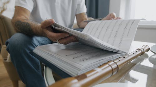 A Flutist Flipping the Pages of a Music Book