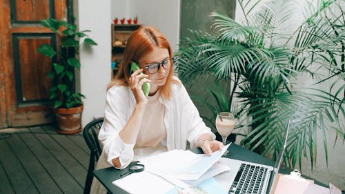 Young Woman Looking at Documents while Speaking on the Phone