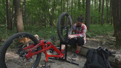 A Man Sitting while Fixing His Bike
