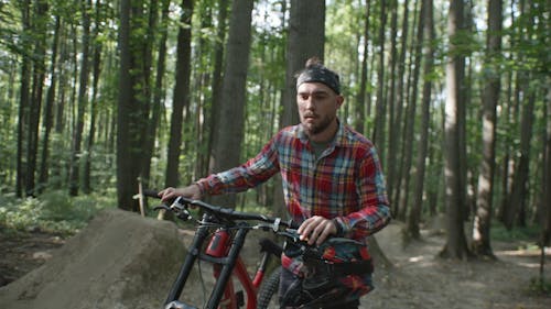 A Man Walking With His Bike in a Forest 