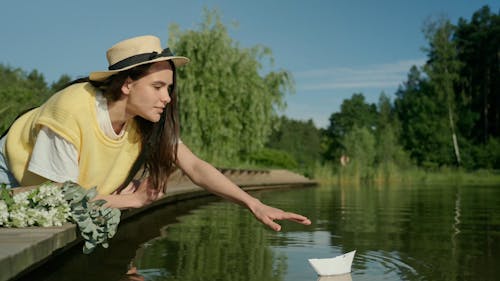 A Woman Playing with a Paper Boat