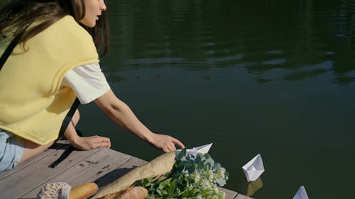 A Woman Launching Paper Boats on a Lake