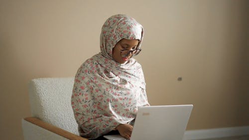 A Woman using a Laptop while Sitting in an Armchair