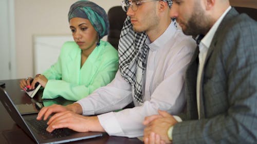 A Man Typing on Laptop with Colleagues on His Side