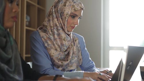 Women Looking at the Screen while Typing on Laptop