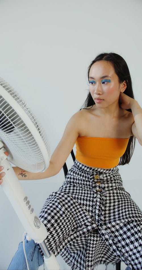 A Woman Holding and Looking at an Electric Fan