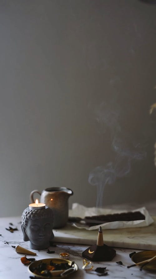 A Buddha Candle Holder and a Burning Incense