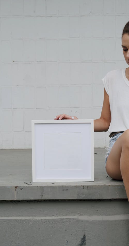 A Woman Sitting while Holding an Empty Frame