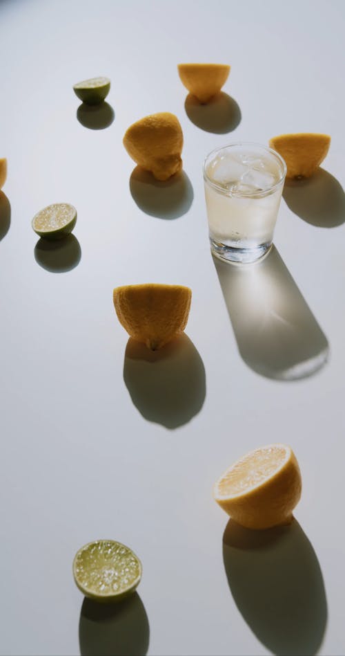 A Glass of Beverage With Sliced Oranges and Limes Around