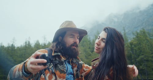 A Couple Kissing while Taking Pictures