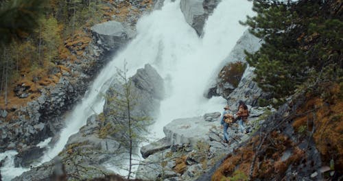 A Couple Standing Beside a Cascading Waterfalls