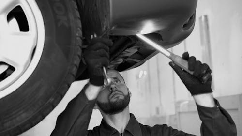 Man Holding a Wrench While Inspecting a Car