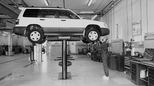 A Mechanic Checking a the Front Tire of a Car