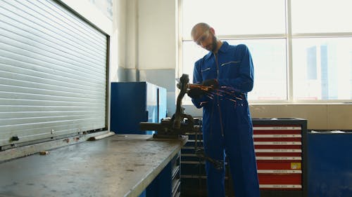 A Man in Coveralls using an Angle Grinder