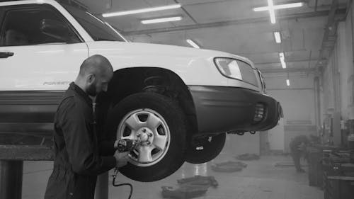 A Man Using an Impact Wrench on a Car