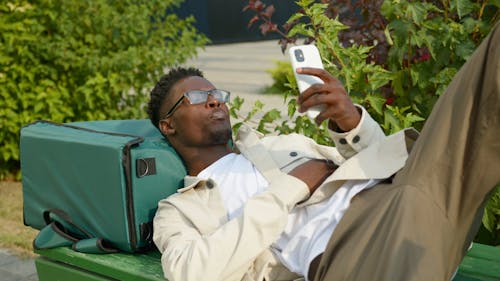 Man Lying on a Bench While Using Cellphone