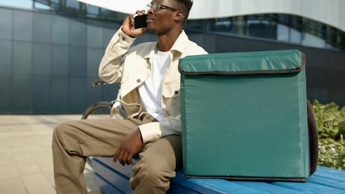 Man Sitting on Bench While Talking on the Phone