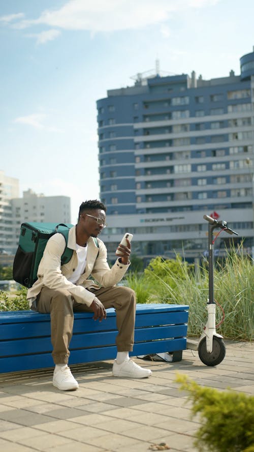 Man Sitting on Bench While Using Cellphone