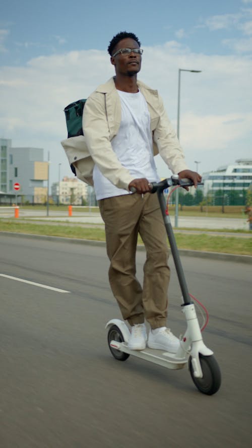 Man Riding a Scooter While Carrying a Thermal Bag