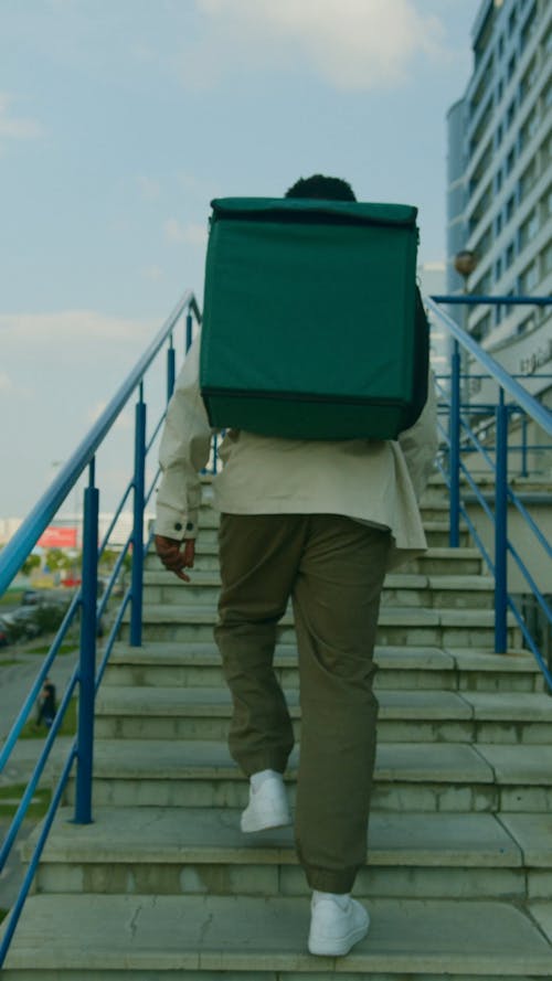 Man Carrying Thermal Bag Going Up the Stairs