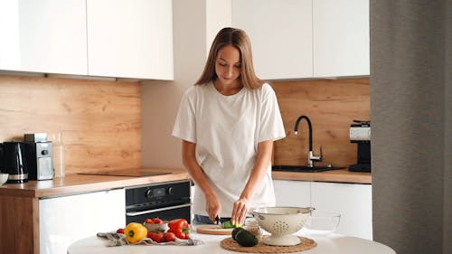 A Woman Slicing a Vegetable Using Knife