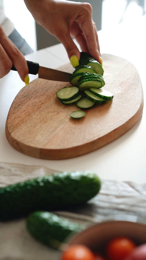 Person Slicing Cucumber with a Knife