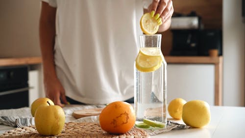 A Person Putting a Sliced Lemon on a Glass of Water