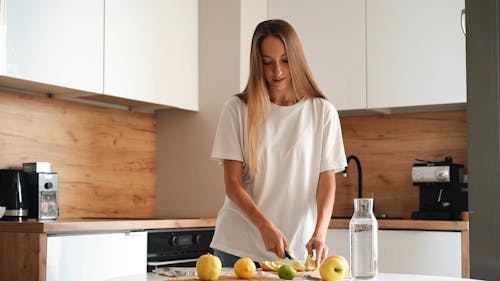 A Woman Wearing White Shirt while Slicing a Lemon